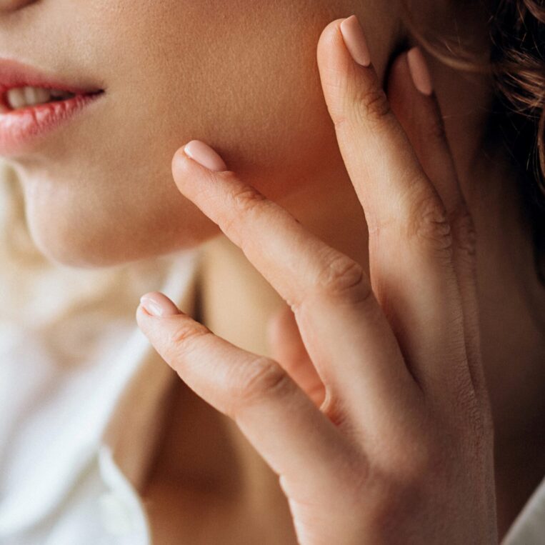 Botox patient touching her masseter muscle that has been treated