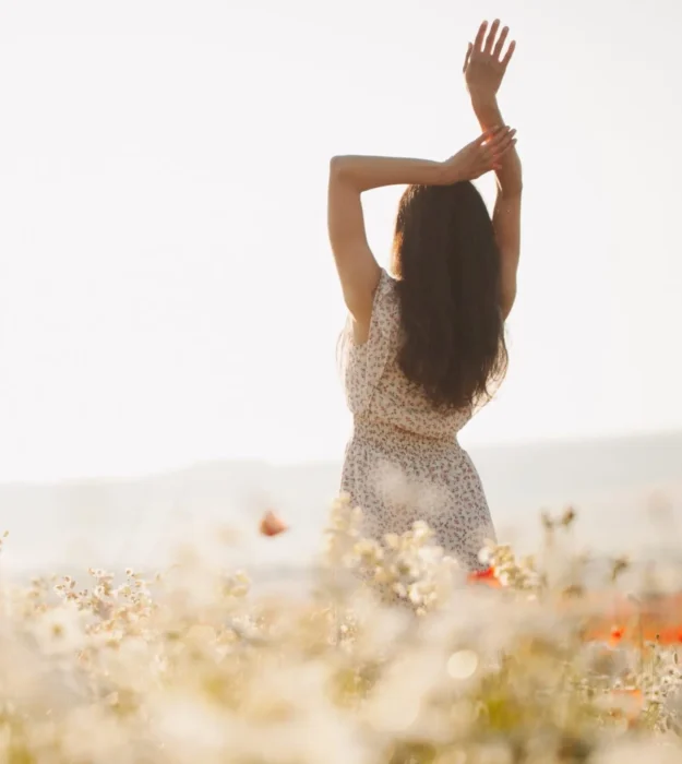 Beautiful girl in summer dress walks in a flower field. Concept of freedom