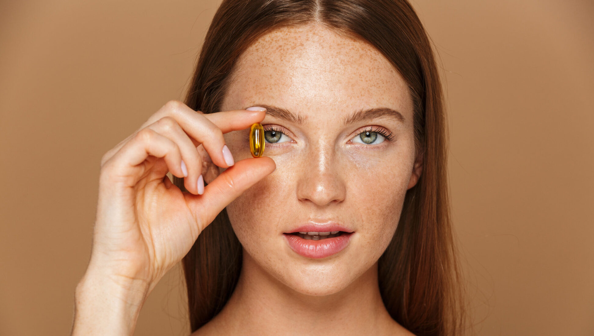 A patient posing with her fish oil pills, muted brown background