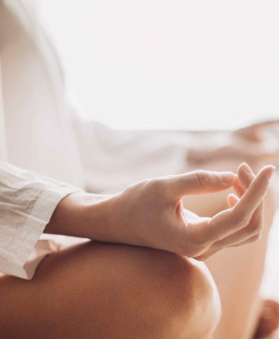 Up-close photo of a woman's hands while she meditates in her living room