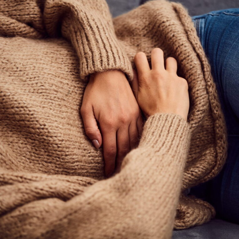 A patient in a brown sweatshirt struggling with gut health symptoms