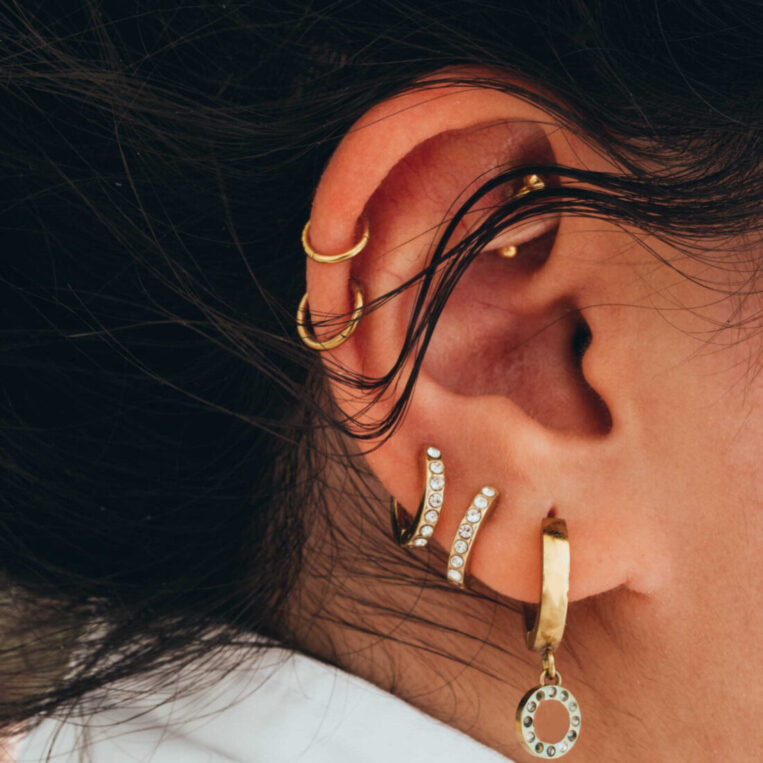 An up-close photo showcasing an woman's ear with multiple ear piercing placements