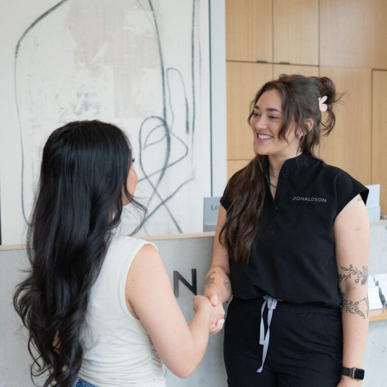 Andie discussing ear piercing aftercare with a patient in the Lewis Center medspa lobby