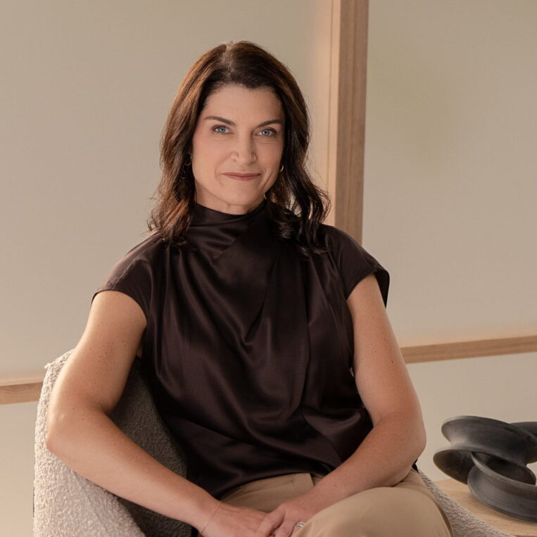 Dr. Weston posing in a chair against a background made up of earth tones
