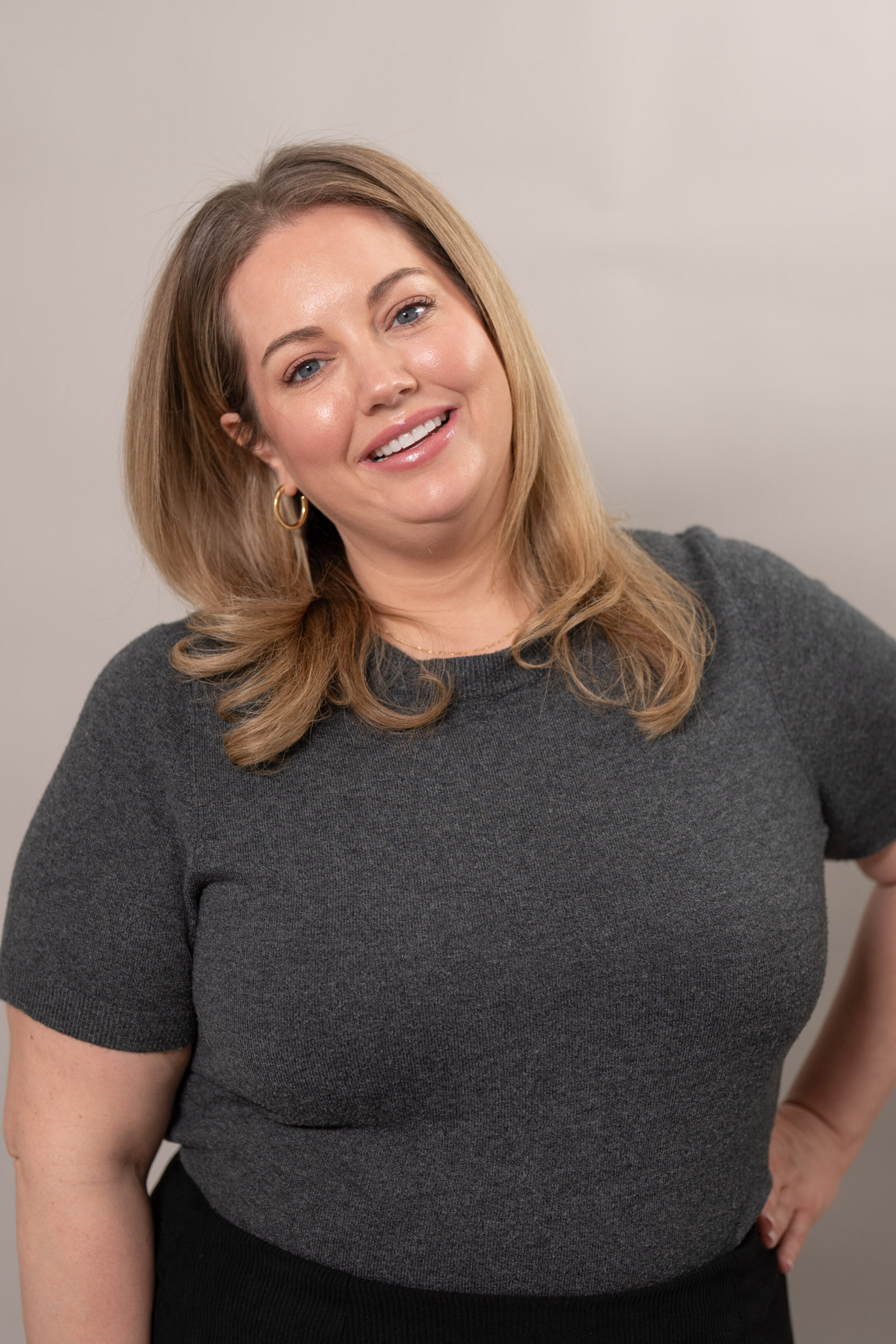 Masseter Botox injection specialist Paige Brudzinski, RN, posing for a photo against a muted gray backdrop