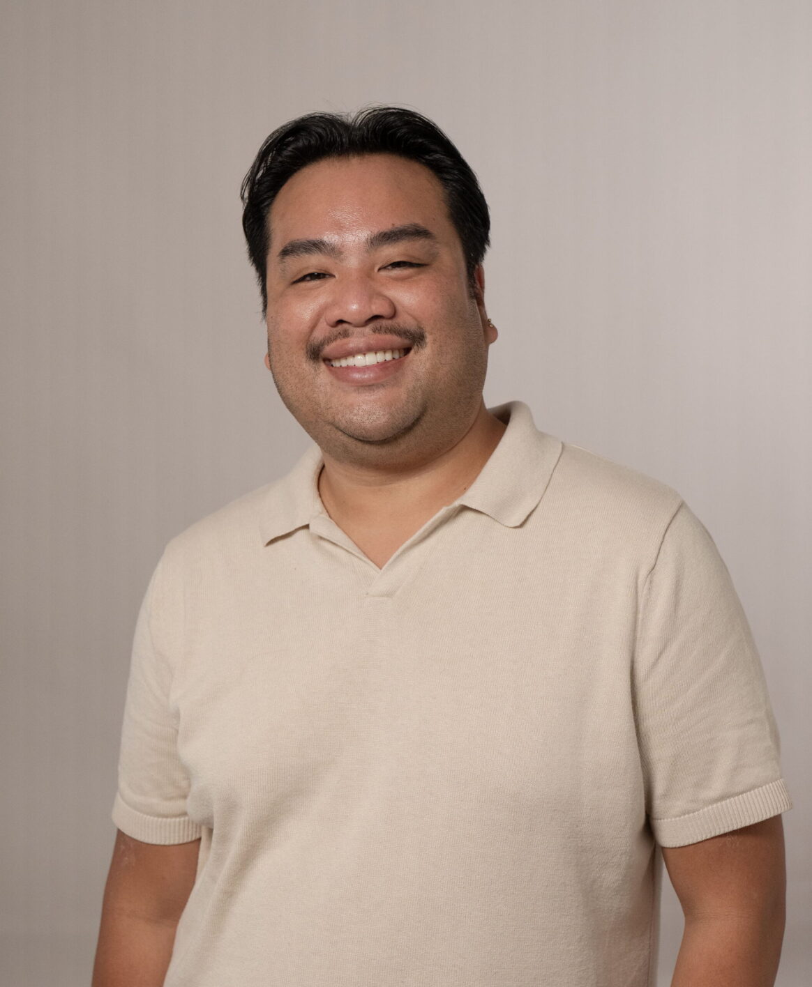 Patrick Thongpasouk posing for a photo against a muted backdrop